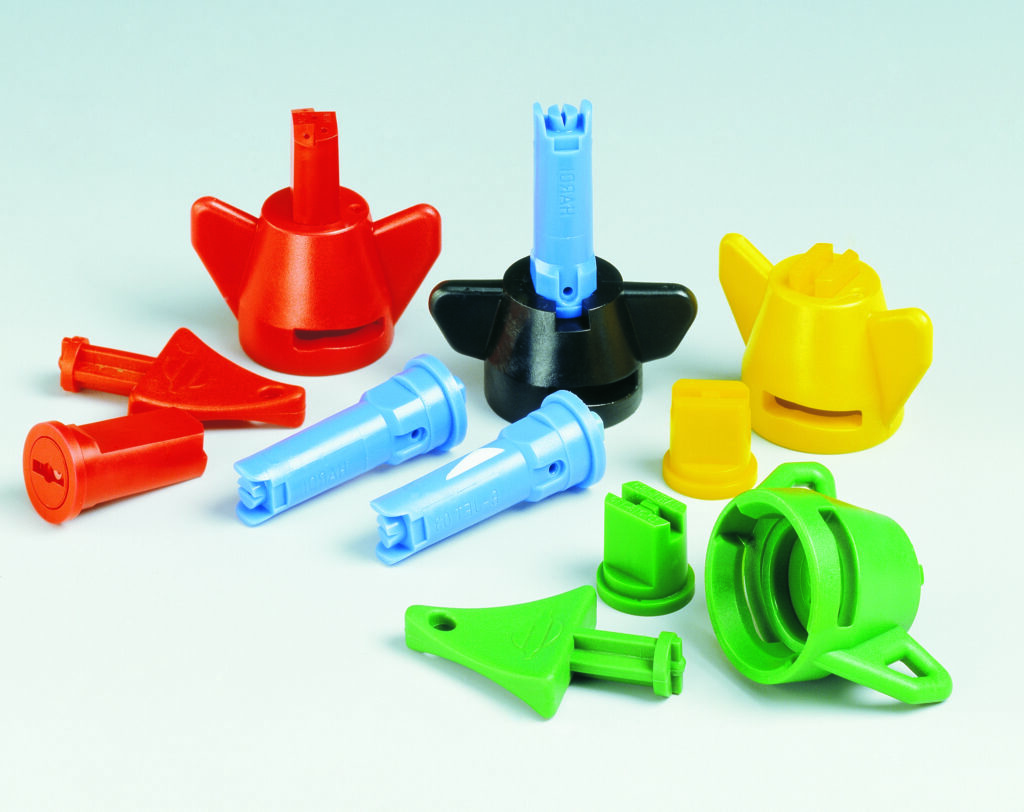 A variety of spray nozzles are shown in different shapes and colours, which are essential tools to minimise spray drift in agricultural practices.